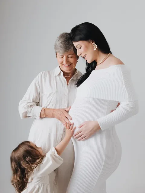 A Dra. Marina gestante, com a mãe e a filha, vestidas de branco